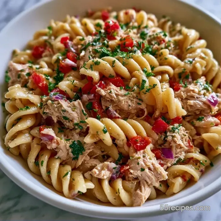 A white ceramic bowl filled with creamy pasta, crisp green peas, and halved tomatoes garnished with fresh parsley.